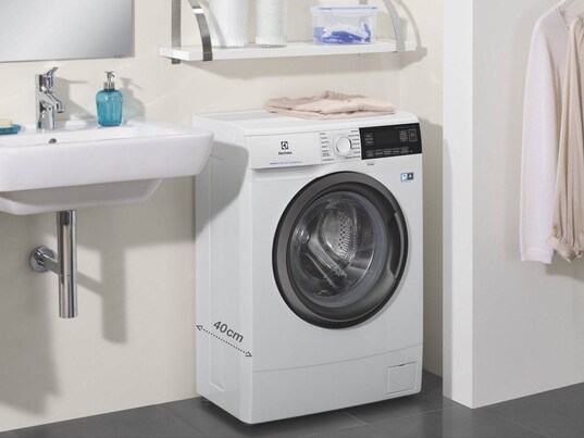 compact white washer in bathroom next to sink