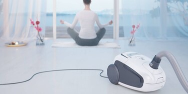 Joogaga tegelev naine koos taustal oleva Electrolux Ultra Silenceri tolmuimejaga