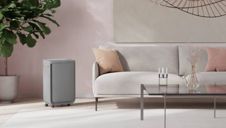 A grey air purifier next to a modern and stylish living room couch